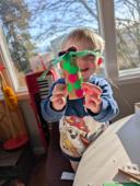 Young child proudly holding a handmade craft project from a Rooted in Writing subscription box activity, shared by a parent reviewer from Seattle, WA.